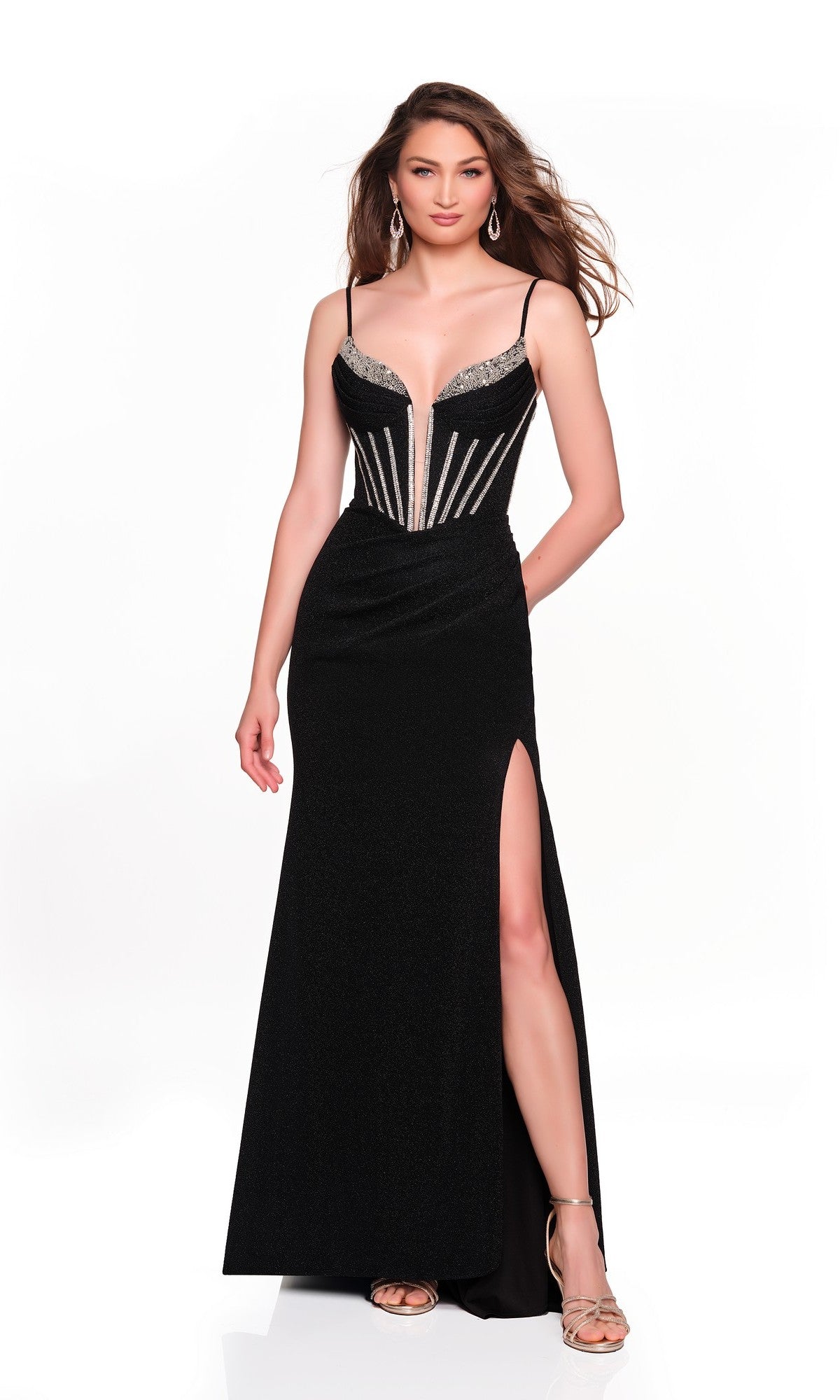 A woman stands against a white background wearing the Dave and Johnny 12804 long prom dress, featuring black fabric, a beaded corset bodice, and a thigh-high slit, paired with strappy heels.